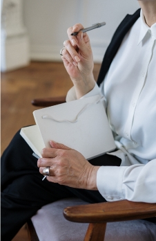 Mujer pensando con boligrafo y cuaderno en las manos