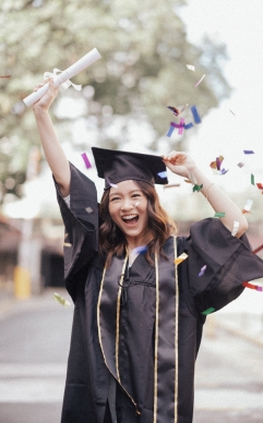 Mujer feliz con toga, birrete y titulo en la mano